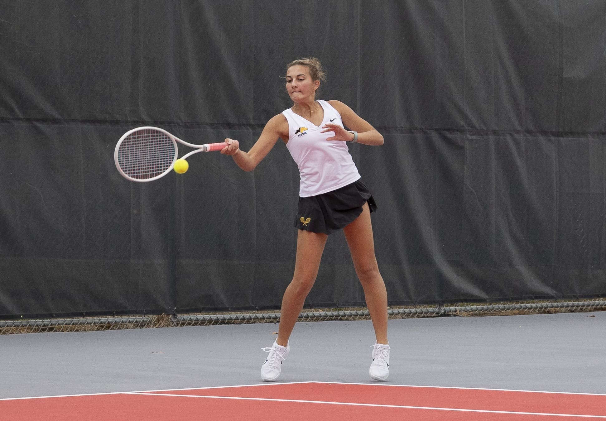 Female tennis player hitting a forehand on a court during a match.