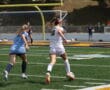 Two female soccer players compete for the ball on a sunny field, focusing on control and agility.