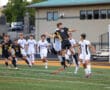 Soccer players in action on the field, mid-air jump for the ball during a high school match.