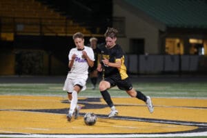 Two soccer players competing for the ball on the field during a night match.
