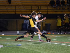 Two soccer players compete for the ball during an intense night match on the field.