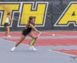 Two female tennis players in action on a bright red court, focusing on returning a tennis ball.