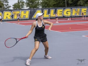 Young female tennis player in action at North Allegheny courts, ready to hit ball with forehand.