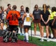 Field hockey team during a match break, players listening to coaches on a sunny day.