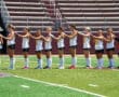 Field hockey team standing in line on a field, wearing uniforms and preparing for the game.