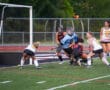 Field hockey players in action near the goal during a competitive match.