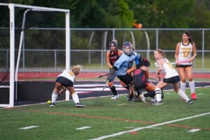 Field hockey players in action near the goal during a competitive match.