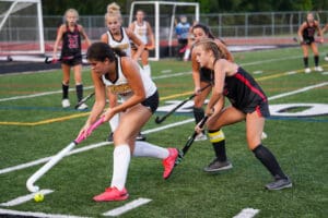 Field hockey players in action during a competitive match on a grassy field.
