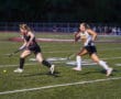 Two field hockey players in action on the field during a competitive match.