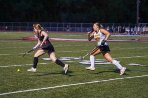 Two field hockey players in action on the field during a competitive match.