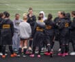 Field hockey team huddling on a field, wearing North Allegheny jackets, ready for a game.