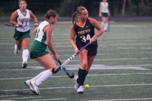 Field hockey players in action during a match, competing for ball possession on the field.