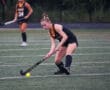Field hockey player in action on the field with a ball and stick, focused and ready to play.