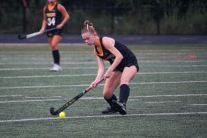Field hockey player in action on the field with a ball and stick, focused and ready to play.
