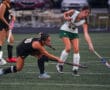 Field hockey players in action, competing intensely on a grassy field during a match.
