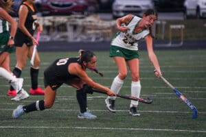 Field hockey players in action, competing intensely on a grassy field during a match.