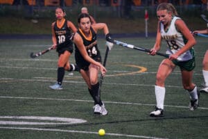 Two field hockey players competing intensely on the field during a match.