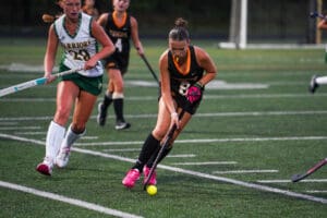 Field hockey players in action on a grassy field during a competitive match, focused and determined.