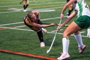 Field hockey players in intense match on green turf.