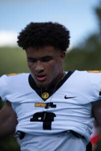 Football player in a white jersey with closed eyes, focused and preparing for the game.