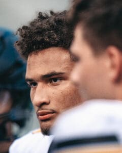 Close-up of a focused athlete on the field, surrounded by teammates.