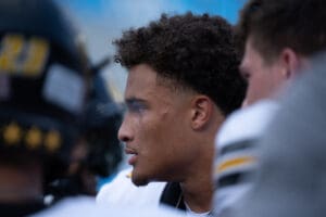 Football player on the sidelines, focused and intense, during a game wearing a black and white uniform.
