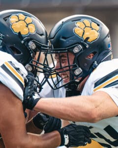 Football players in helmets engage in a passionate pre-game ritual, showcasing team spirit and camaraderie.