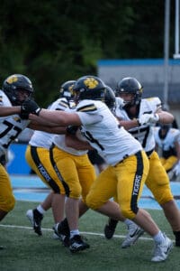 Football players in Tigers uniforms practicing blocking drills on the field.