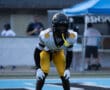 Football player in yellow pants and black helmet prepares on field during game.