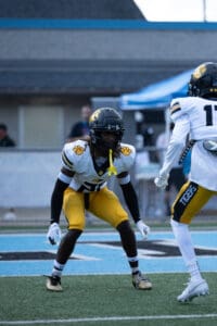 Football player in yellow pants and black helmet focuses during a game on the field.