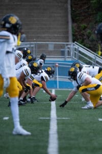 High school football teams face off at the line of scrimmage, ready for the play to begin.