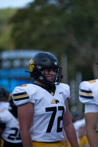 Football player in black helmet and white jersey number 72 on the field.