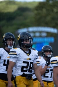 Football players in yellow and white uniforms, gathering on the field, ready for the game.