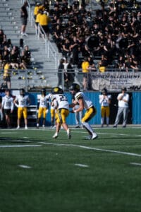 Football players on the field with spectators and band in the background during a game.