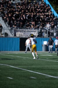 Football player number 4 running on field with cheering crowd in background.