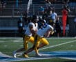 Football players in yellow uniforms preparing for a play on the field during a game.