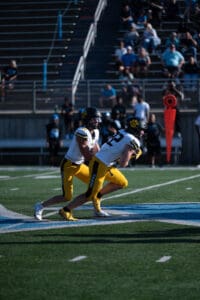 Football players in yellow uniforms preparing for a play on the field during a game.