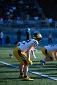 Football player in yellow Tigers uniform on field, ready to play during a game.