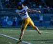 Football player #22 in mid-air catch during a game, wearing a yellow and black uniform on the field.