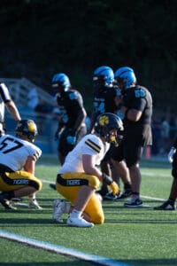Football game action with players in yellow and black uniforms preparing for play on the field.