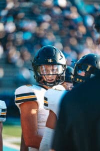 Football player in helmet and jersey on the field, focused during a game.