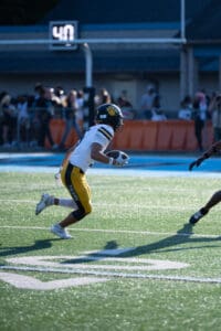 High school football player in action running with the ball during a game.