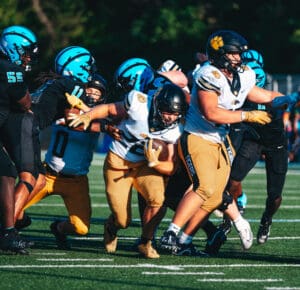 Football players in action, athletes in black and white jerseys competing intensely on the field.