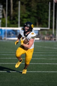 Football player in yellow running with ball on field during game.