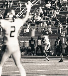 Football game action shot with player catching ball, audience watching intensely from stadium stands.