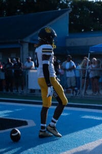 Football player in end zone during game, wearing yellow and black uniform, helmet with paw logo, with crowd in background.