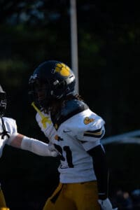 Football player in black helmet with yellow paw logo during a game, wearing white and yellow uniform.