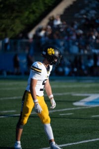 Football player in yellow pants and black helmet on field during daytime game.