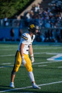 Football player in yellow and white uniform ready on the field during a game.