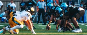 Football teams face off on the field, preparing for play with intense focus and determination.